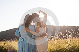 Two adult girlfriends hug each other at the background of nature