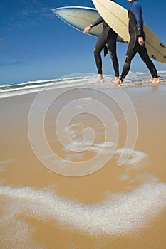 Two adult males carrying surf boards