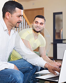 Two adult men with laptop indoors