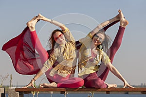 Two adult women aged yoga outdoors in summer in the park