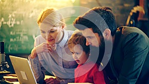 Two adults and a boy watching a movie on a laptop. Concept of the educational process. Teacher in classroom. Teacher and