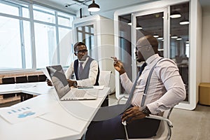 Two African American business partners are working on a laptop together on a common project. Coworking, social contacts