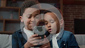 Two African American little boys brothers addicted to modern technology happy laughing children kids siblings using