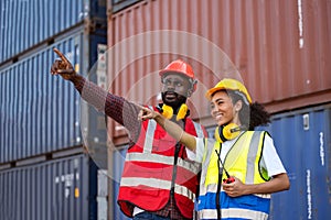 Two African american male and female worker check and control loading freight containers from Cargo freight ship for import export