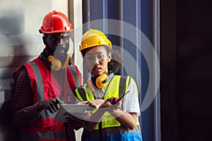 Two African american male and female worker using tablet and checking control loading freight containers from Cargo freight ship