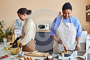 Two African American women doing food prep in kitchen cooking together