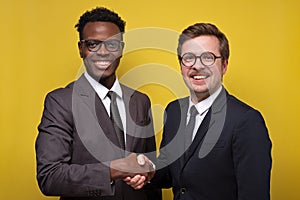 Two african and caucasian businessmen smiling and shaking hands
