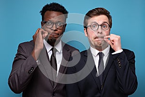 Two african and caucasian men shut mouth as zip with fingers