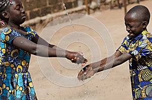 Two African Children Cleaning Hands Outdoors with Fresh Water