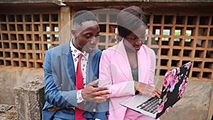 Two african colleagues discuss a project working with laptop, elegant female and male coworkers at work