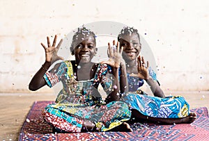 Two African Girls Sisters Friends wear traditional Clothes Posing indoor white room and with confetti