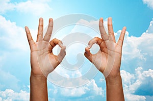 Two african hands showing ok sign over blue sky