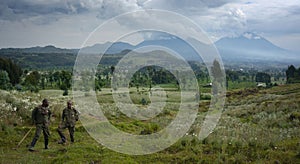 African military men standing in a green grassy landscape with hills in the background