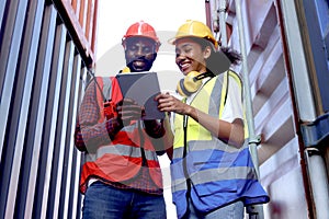 Two African workers wear safety vest and helmet at logistic shipping cargo containers yard. Happy young engineer woman uses