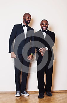Two afro-american businessmen in black suits emotional posing, gesturing, smiling. wearing bow-ties entertaiment stuff