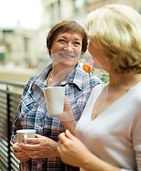 Two aged housewives with cup of tea at terrace