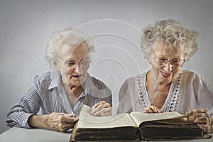 Two aged woomen reading a book