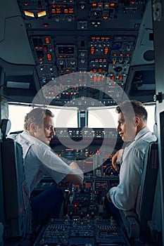 Two airmen dressed in uniforms sitting in the cockpit