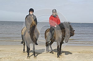 Two amazones on horseback on the beach