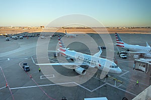 two american airlines planes parked at DFW International airport with the runway behind during sunset