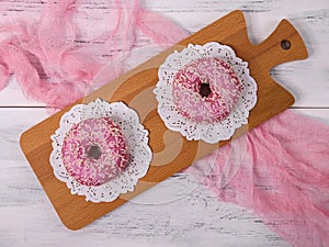 Two american donuts with pink icing.