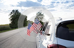 Two American flags hanging out of the car window. USA Independence Day July 4th
