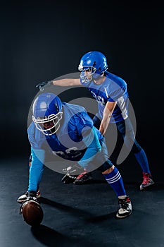 Two American football players are ready to start the game on a black background.