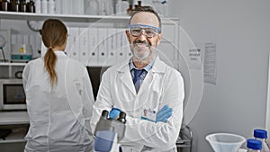 Two amiable scientists, best mates, sitting with arms crossed, engrossed in serious lab work in a bustling medical research