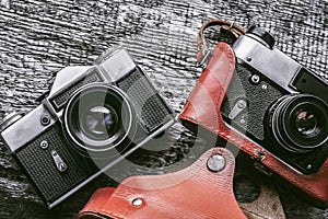 Two analog retro cameras lie on an old wooden table. Illustration