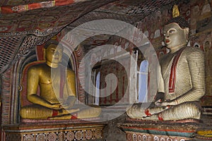 Two ancient statues of seated Buddha in ancient Buddhist cave temple. Sri Lanka