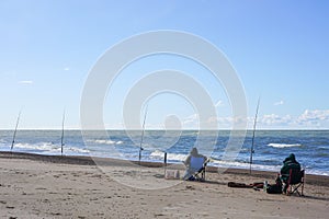 Two anglers catch fish by the sea, rear view