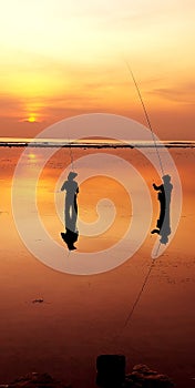 Two anglers chatting while enjoying the sunrise at Sanur beach