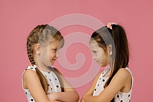 Two angry little girls in dress looking at each other