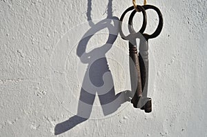 Two antique skeleton keys hanging from a white wall