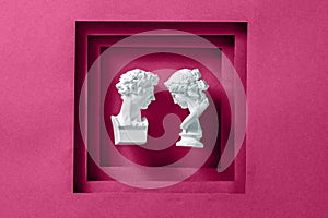 Two antique statues as a young romantic couple framed with a magenta background as a minimal concept of love, happiness