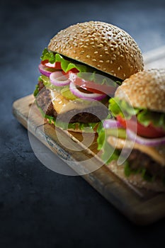 Two appetizing burgers on a wooden plank