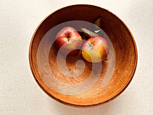 Two apples in a grained wooden bowl. Red and green apples.