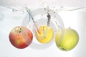 Two apples and lemon splash in water on white