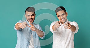 Two Arab Men Pointing Fingers At Camera On Turquoise Background