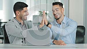 Two Arab young male businessmen sitting in modern office, satisfied with result of negotiations, having concluded