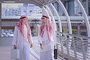 Two arabian business men discuss and walk together around modern