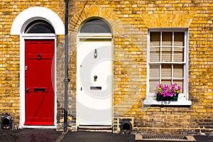 Two arch doors red and white. Typical British front of the house entrance. Exterior of old house with flowers and plants