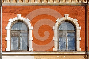 Two arched windows on a brick wall