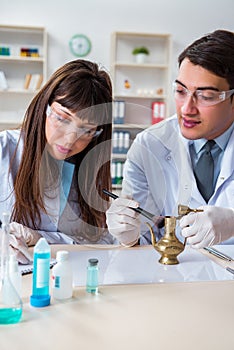 The two archeologists looking at ancient gold lamp