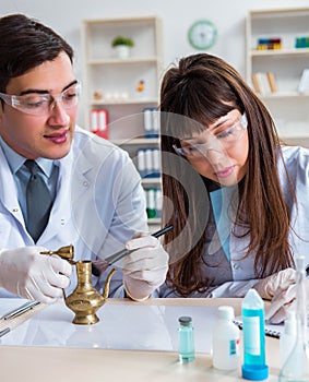 Two archeologists looking at ancient gold lamp