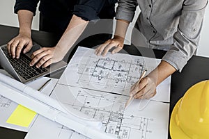 Two architects and engineers are in a meeting to discuss and inspect the house designs to meet the building and construction