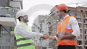 Two architects engineers shaking hands at construction site. Professions, construction, workers, architect concept.