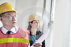 Two architects in protective workwear and hardhats working in an office building