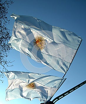 Two Argentine flags moving in the blue sky.