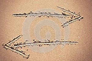 Two arrow signs drawing in sand background